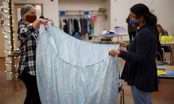 Teacher and student fold a sheet
